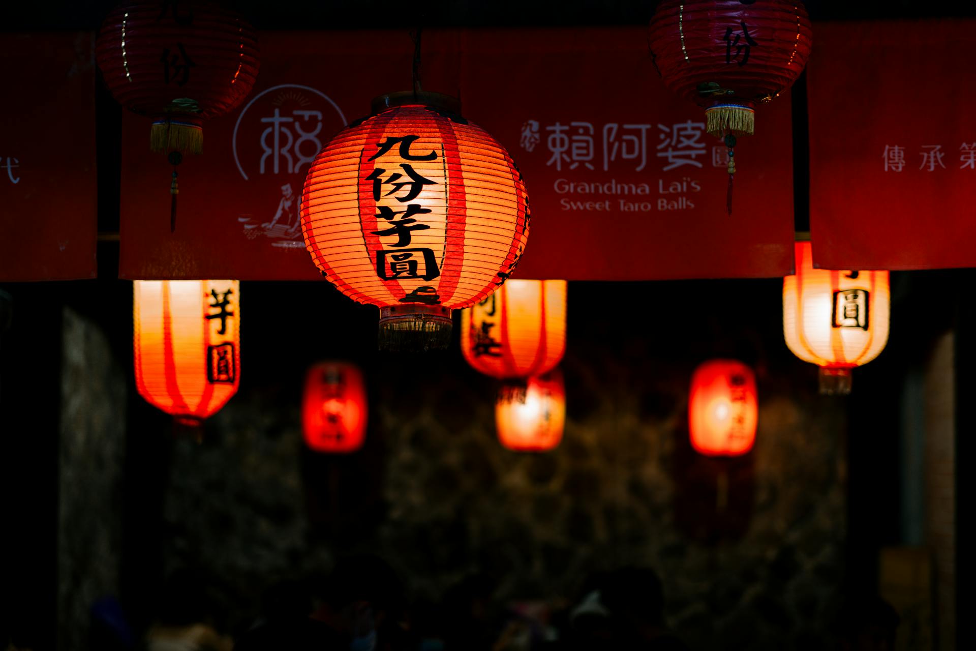 Red lanterns illuminate a Chinese night market, adding a cultural and festive ambiance.