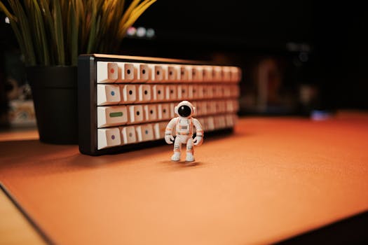 A small astronaut toy on a desk near a keyboard and plant, perfect for space-themed decor.