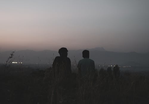 Friends Sitting on a Hill Outside the City at Dusk