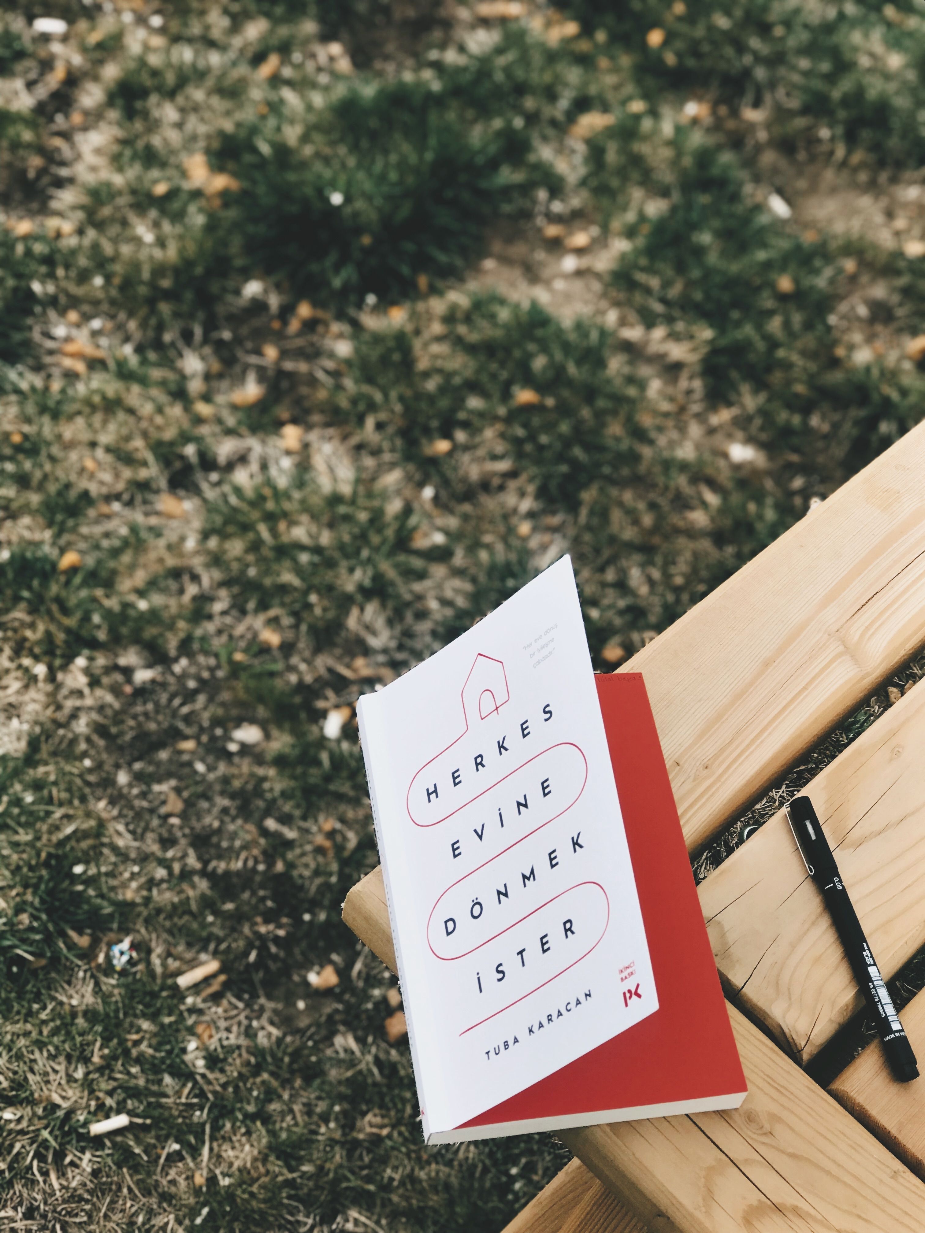 A book and pen resting on a bench, perfect for outdoor reading and relaxation.