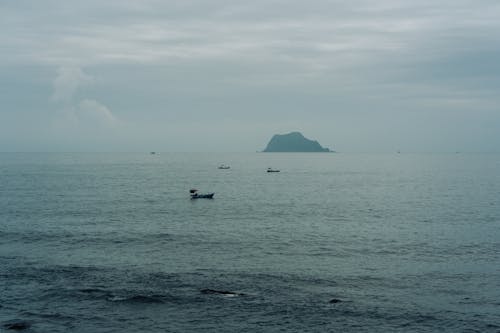 Boats on the Sea and an Island in the Horizon