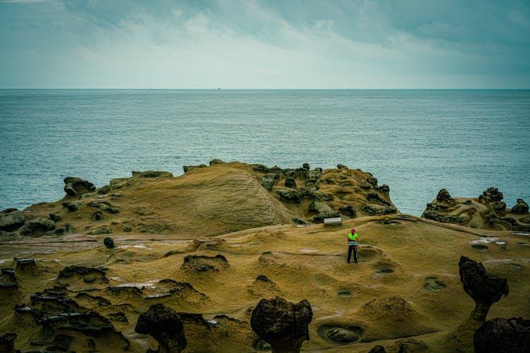 Person Standing Atop Eroded Rock Formations In Yehliu Geopark, Taiwan