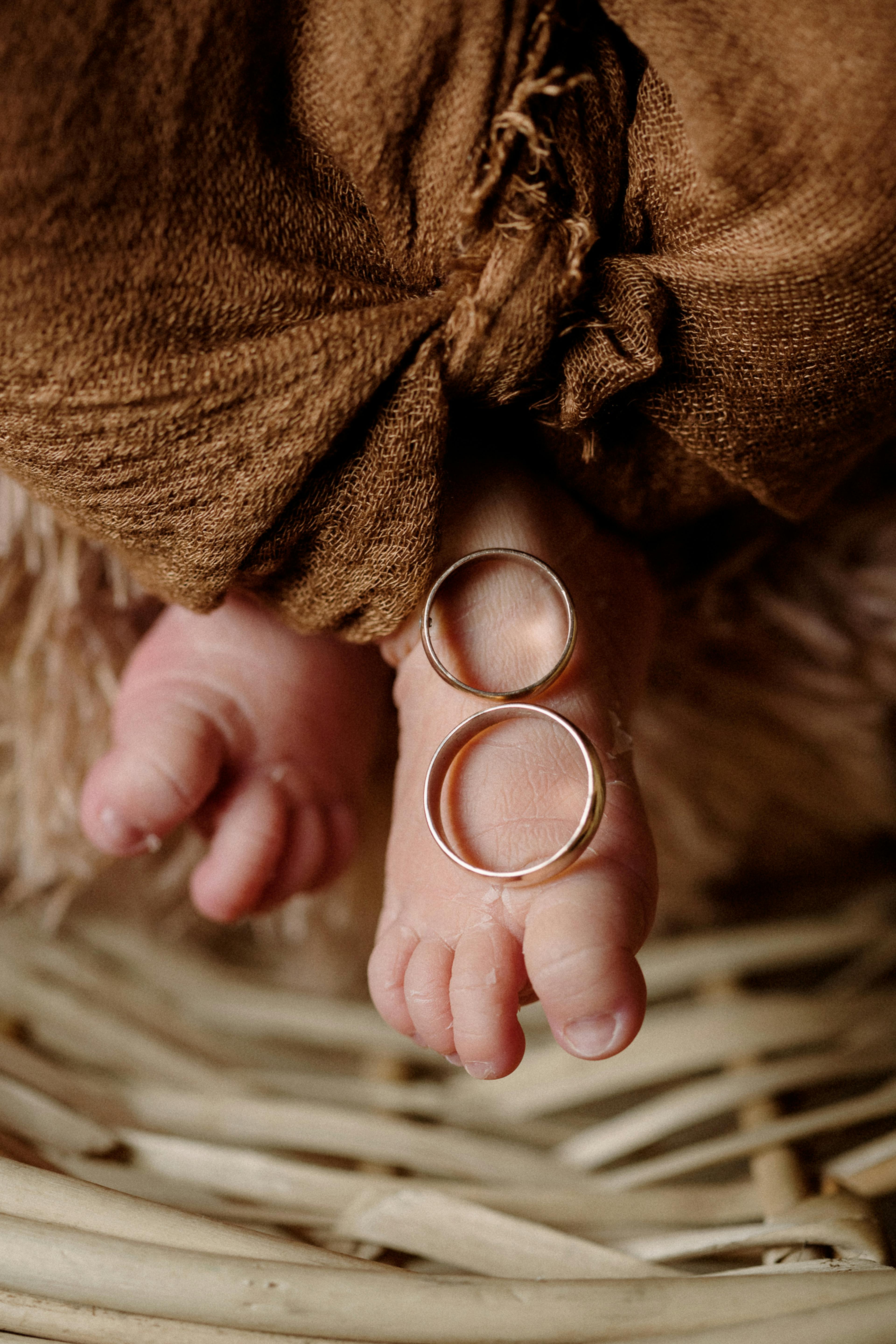 Close-up of baby feet adorned with wedding rings, symbolizing love and innocence.