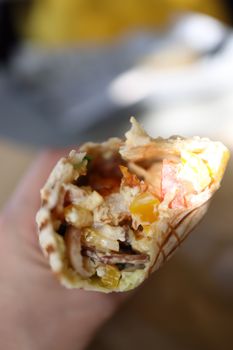 A delicious freshly made burrito held in hand, featuring vibrant ingredients.