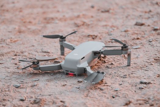 Close-up of a modern drone resting on sandy terrain, highlighting technology and exploration.