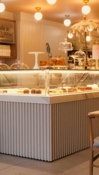 Warm and inviting cafe interior featuring illuminated dessert display with modern decor.