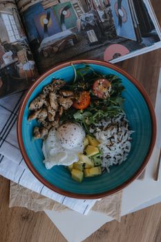 Top view of a colorful rice bowl with grilled chicken, vegetables, and a poached egg, perfect for a healthy meal.