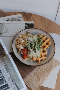 Savory chicken waffle salad with cherry tomatoes and greens on a rustic table setting.
