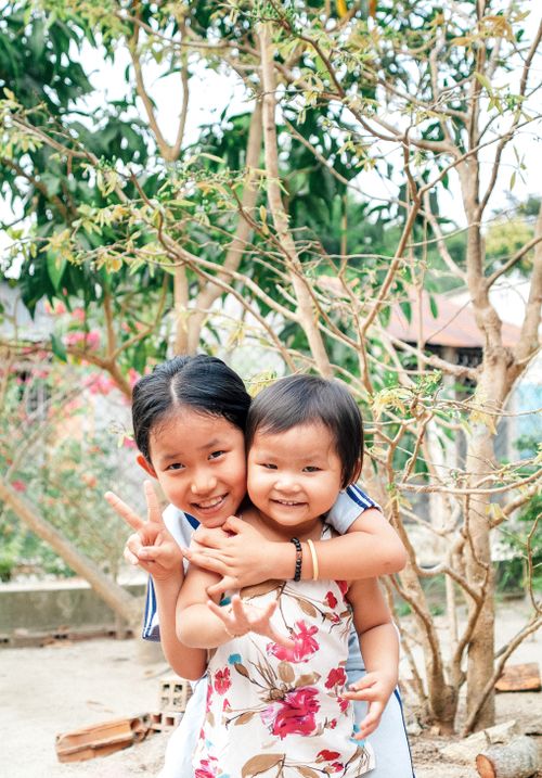 Free Two young sisters happily posing together outdoors in An Giang, Vietnam. Stock Photo