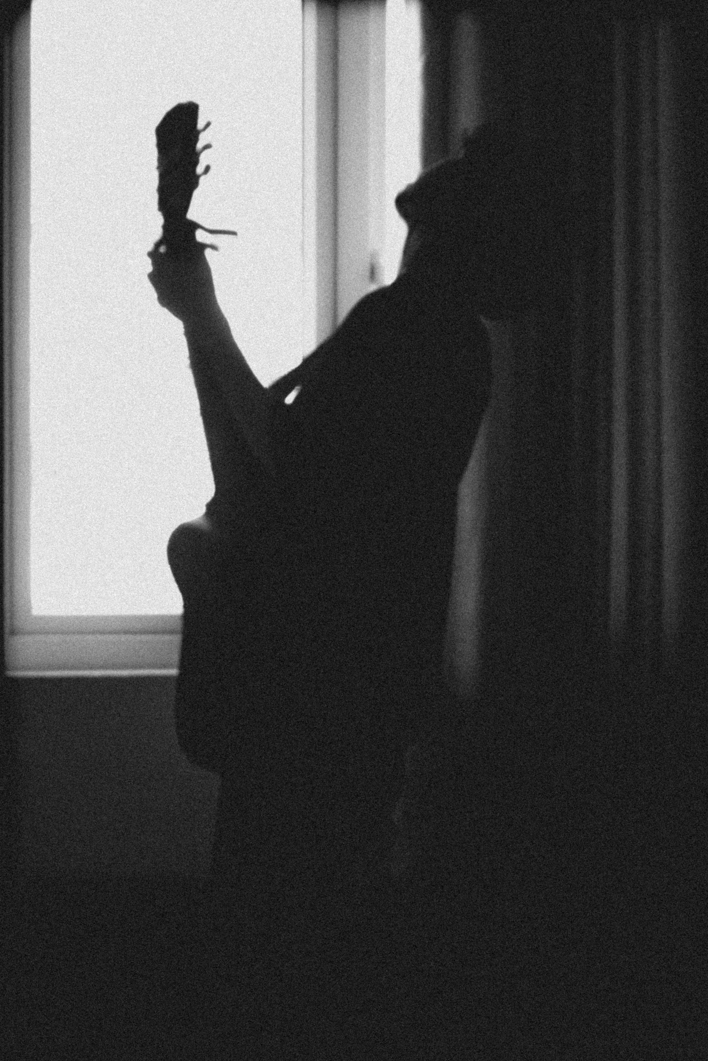 Silhouette of a guitarist playing by a window creates a moody and artistic atmosphere.