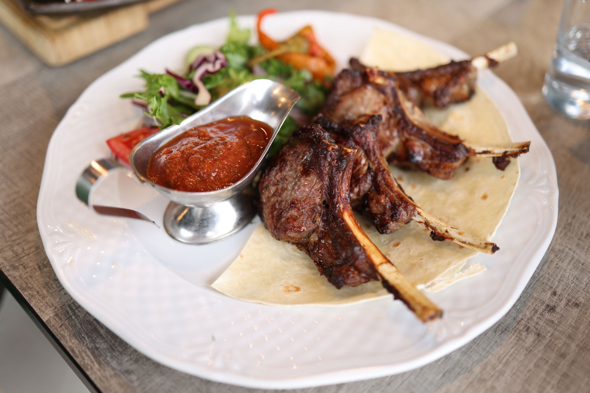 25 Must-Try Summer Grilling Recipes for Your BBQ Juicy roasted lamb chops served with fresh salad and spicy sauce on a plate.