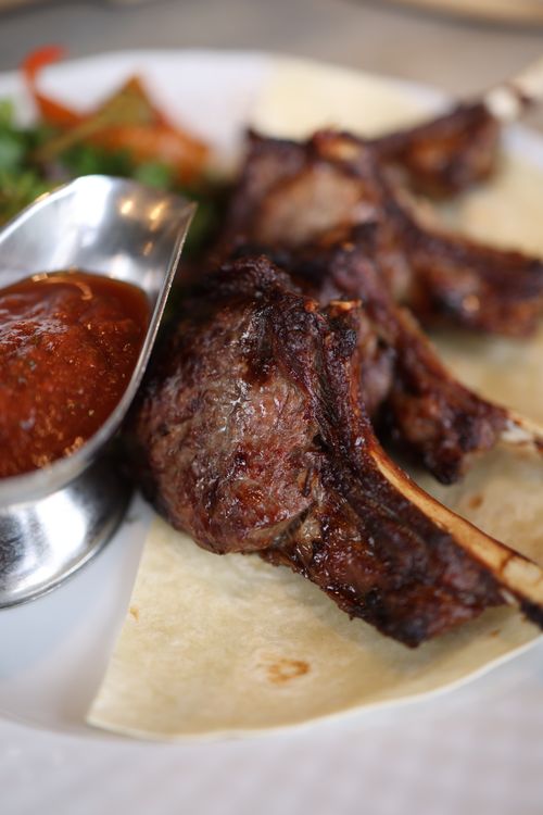 Free Close-up of grilled lamb chops served with sauce on a plate, perfect for gourmet meal lovers. Stock Photo