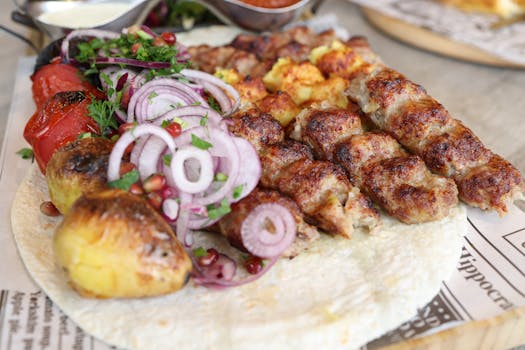 Close-up of grilled meat and vegetables served on flatbread, garnished with fresh herbs and onions.