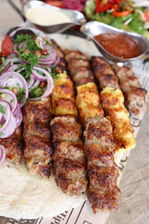 Free Close-up of succulent grilled kebabs with vegetables and sauces, perfect for dinner. Stock Photo