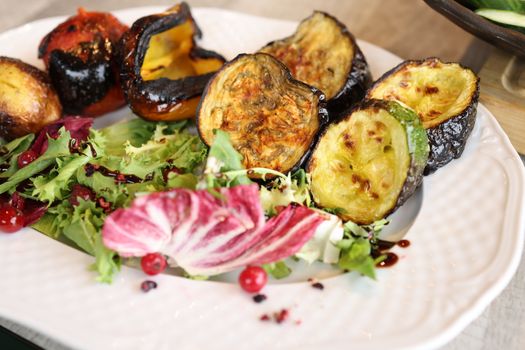 A vibrant close-up of grilled vegetables and fresh salad on a plate.