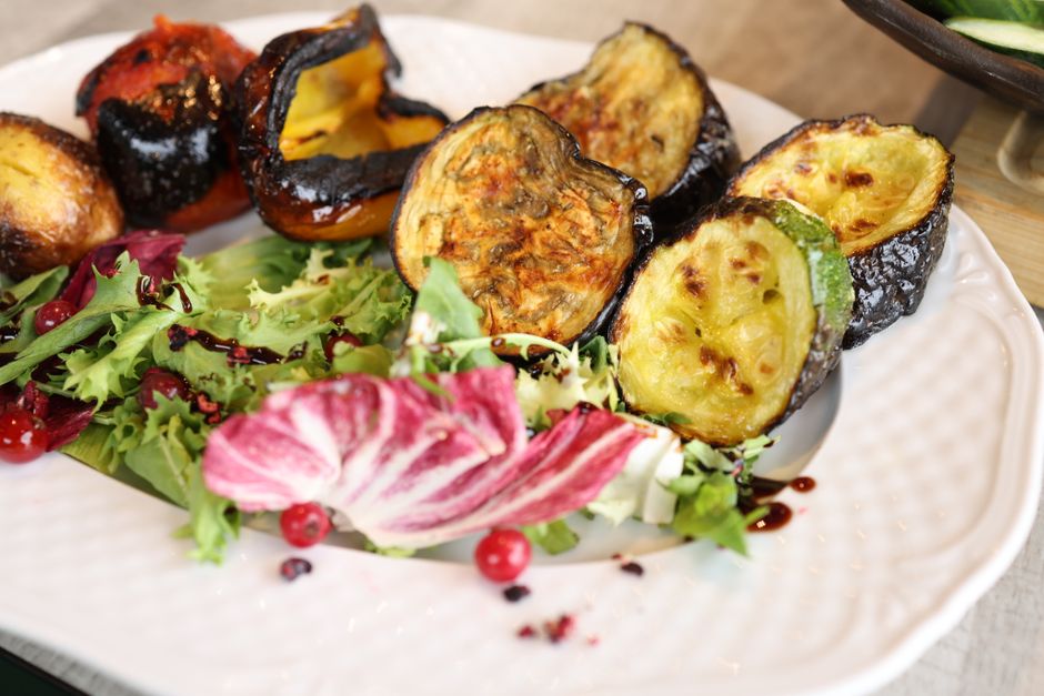 A vibrant close-up of grilled vegetables and fresh salad on a plate.