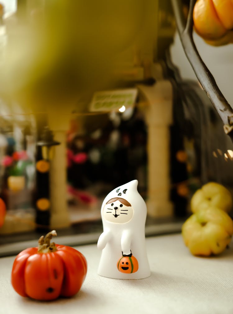 Figurine Of A Cat Dressed As A Ghost Carrying A Jack-o-Lantern On The Kitchen Counter