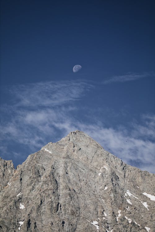 A moon is seen above a mountain peak