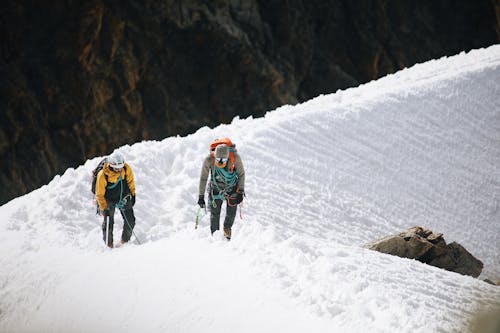 Two people walking up a snowy mountain