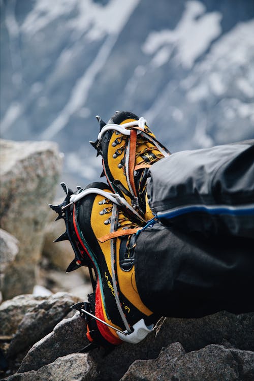 A person wearing yellow and black hiking shoes on top of a mountain