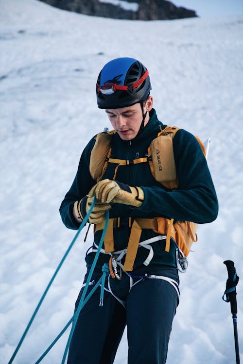 A man in a helmet and gloves is holding a rope