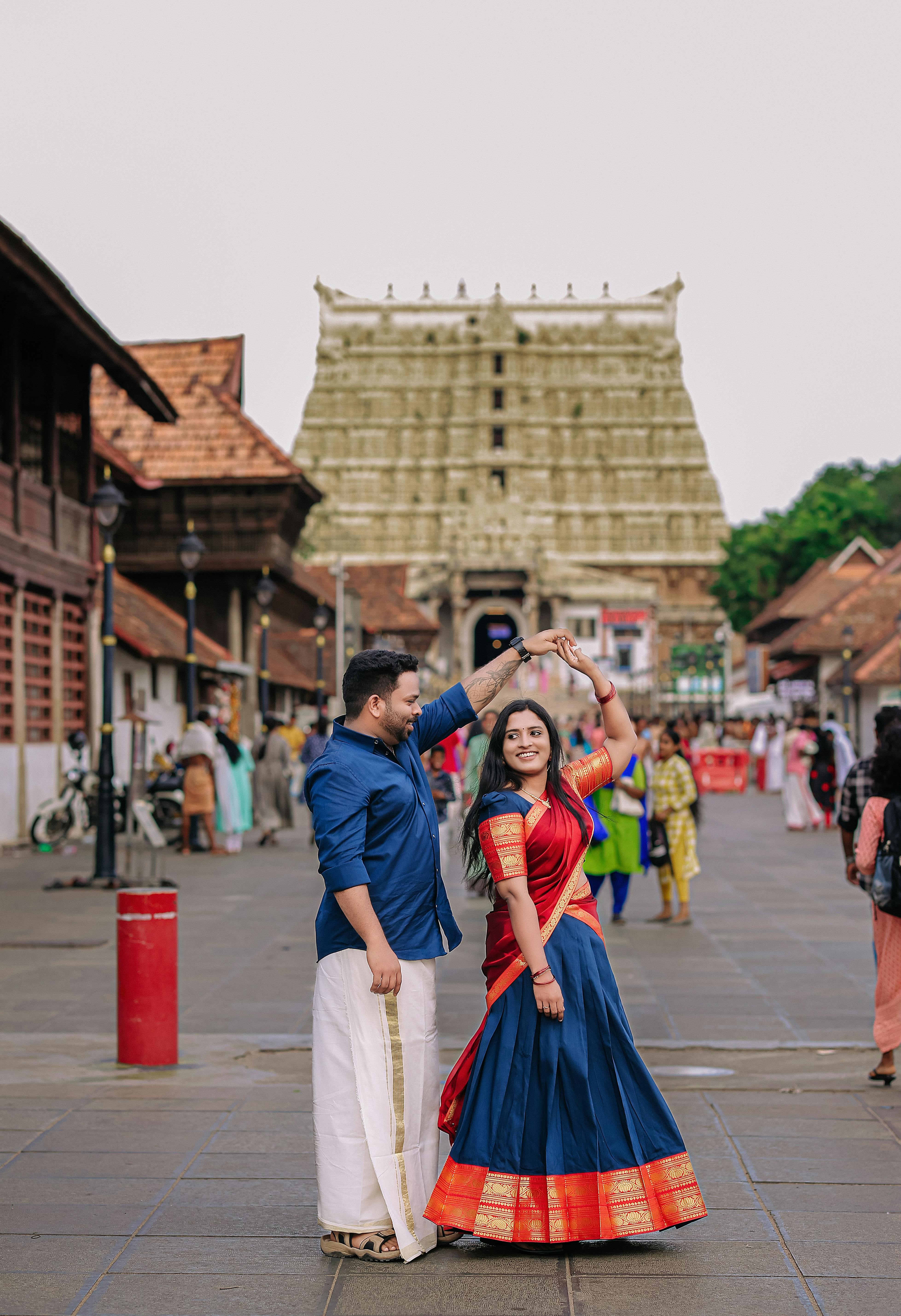 A couple in traditional attire dancing joyfully outside Padmanabhaswamy Temple in Thiruvananthapuram, India.