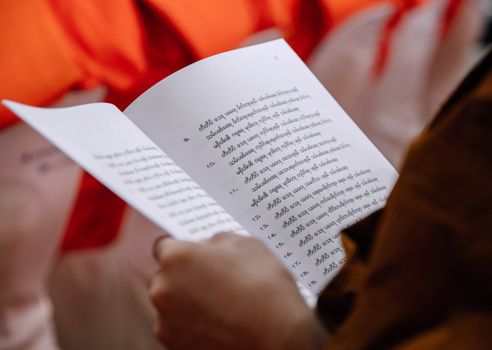 Close-up of a Buddhist monk reading sacred texts during a religious ceremony in Thailand.