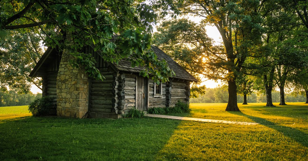 A charming log cabin nestled among trees with a beautiful sunset glow in Lund, Wisconsin.