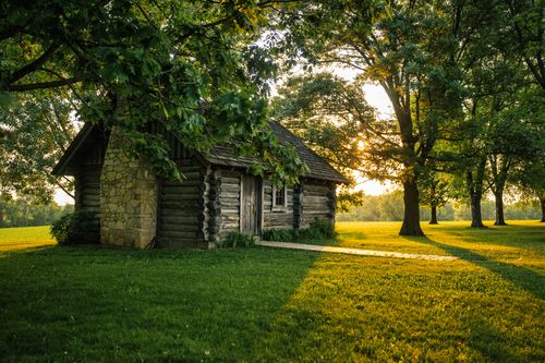 Free A charming log cabin nestled among trees with a beautiful sunset glow in Lund, Wisconsin. Stock Photo
