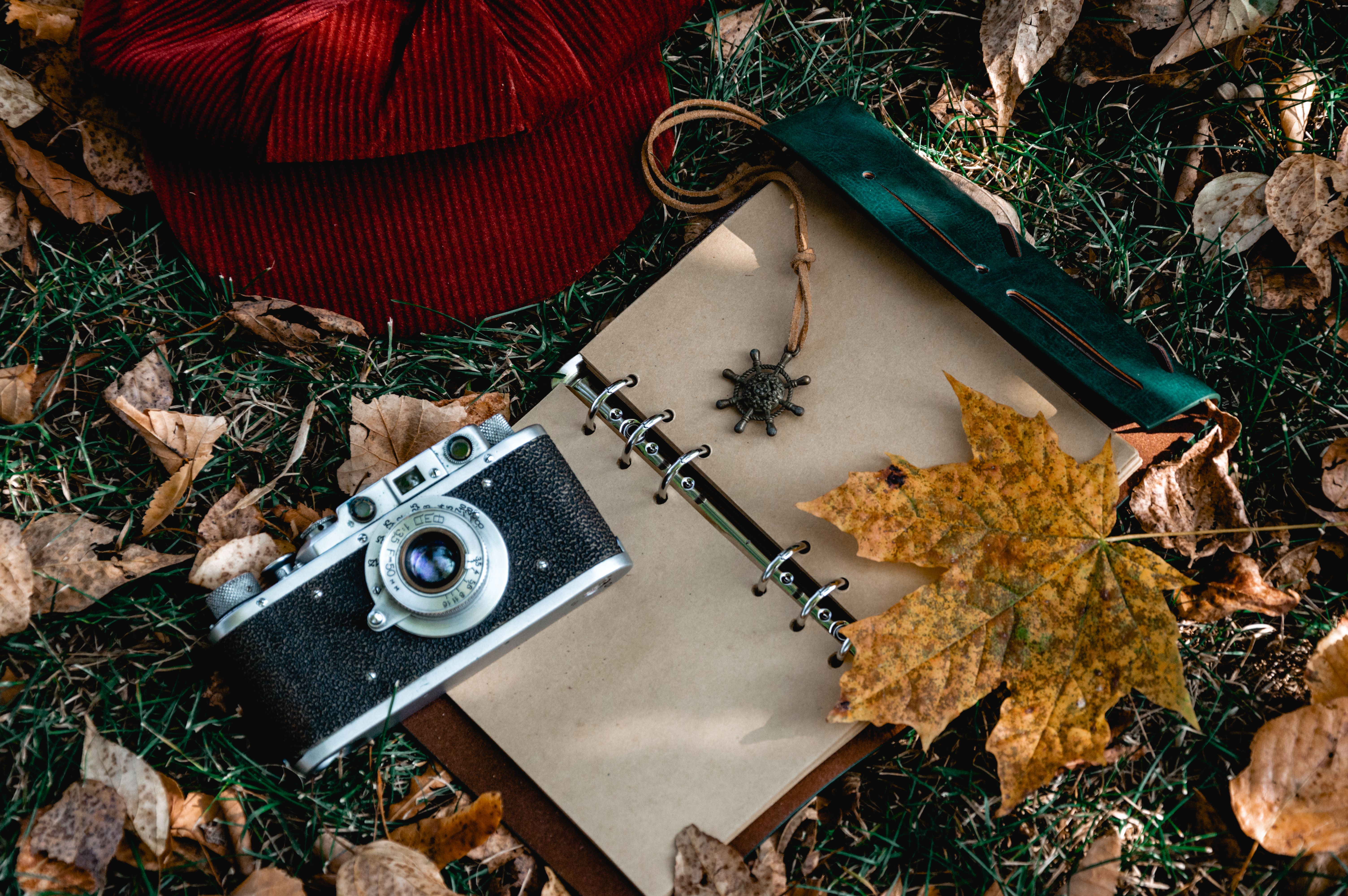 A classic camera with autumn leaves and notebook, evoking a nostalgic mood.