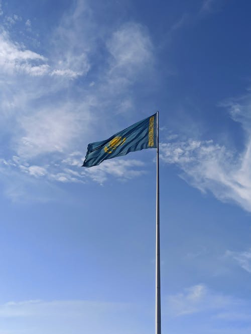 Flag of Kazakhstan on a Flagpole on the Background of Blue Sky
