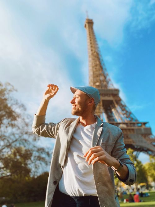 Free Smiling man enjoys a sunny day near the Eiffel Tower in Paris, France. Stock Photo