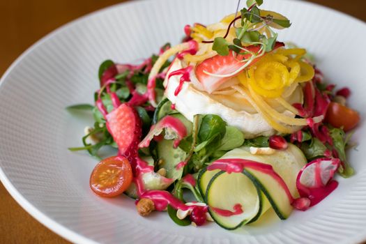 A fresh and colorful vegetable salad with gourmet cheese, perfect for summer dining.