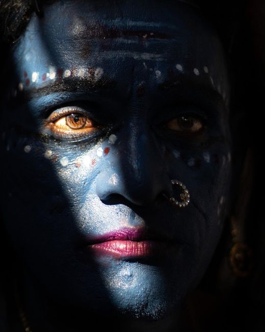 Close-up portrait of a man with traditional face paint in shadows. Captivating and cultural.