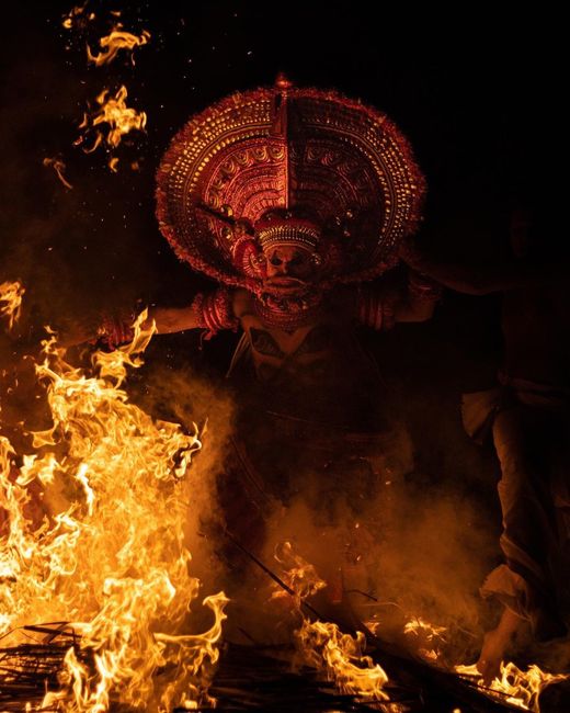 Capture of a vibrant Theyyam ritual with fire in Kerala, India at night.