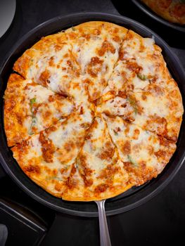 Fresh pizza with melted cheese and toppings in a pan, viewed from above - ideal for food enthusiasts.