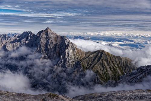 Free Majestic mountain peaks surrounded by clouds under a dramatic sky. Stock Photo