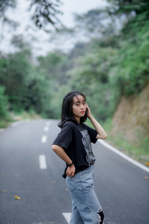 A Girl in a Casual Outfit Standing on an Asphalt Road