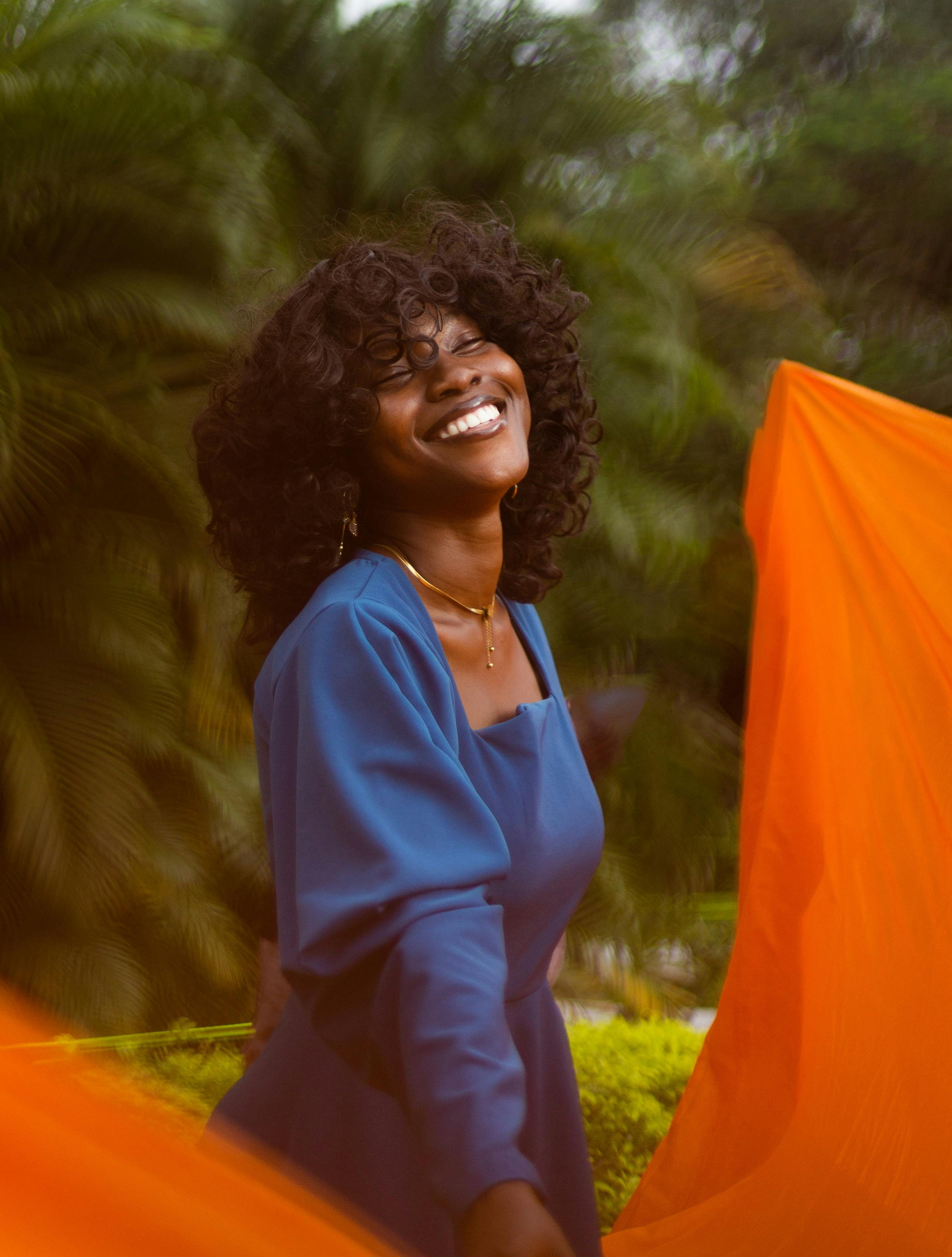Captivating portrait of a joyful woman in a blue dress, posing outdoors in vibrant Lagos, Nigeria.