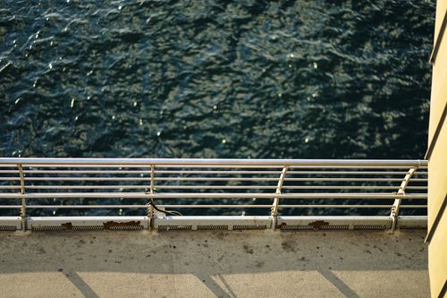 Free Perspective from a ship's deck, showcasing the ocean and metal railing in soft daylight. Stock Photo