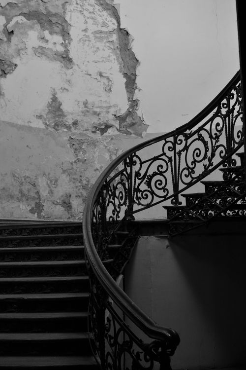 Free Black and white image of a vintage wrought iron staircase in an old residential building. Stock Photo