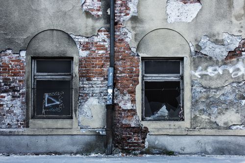 Free A decaying brick wall with arched windows and graffiti, showcasing urban decay. Stock Photo