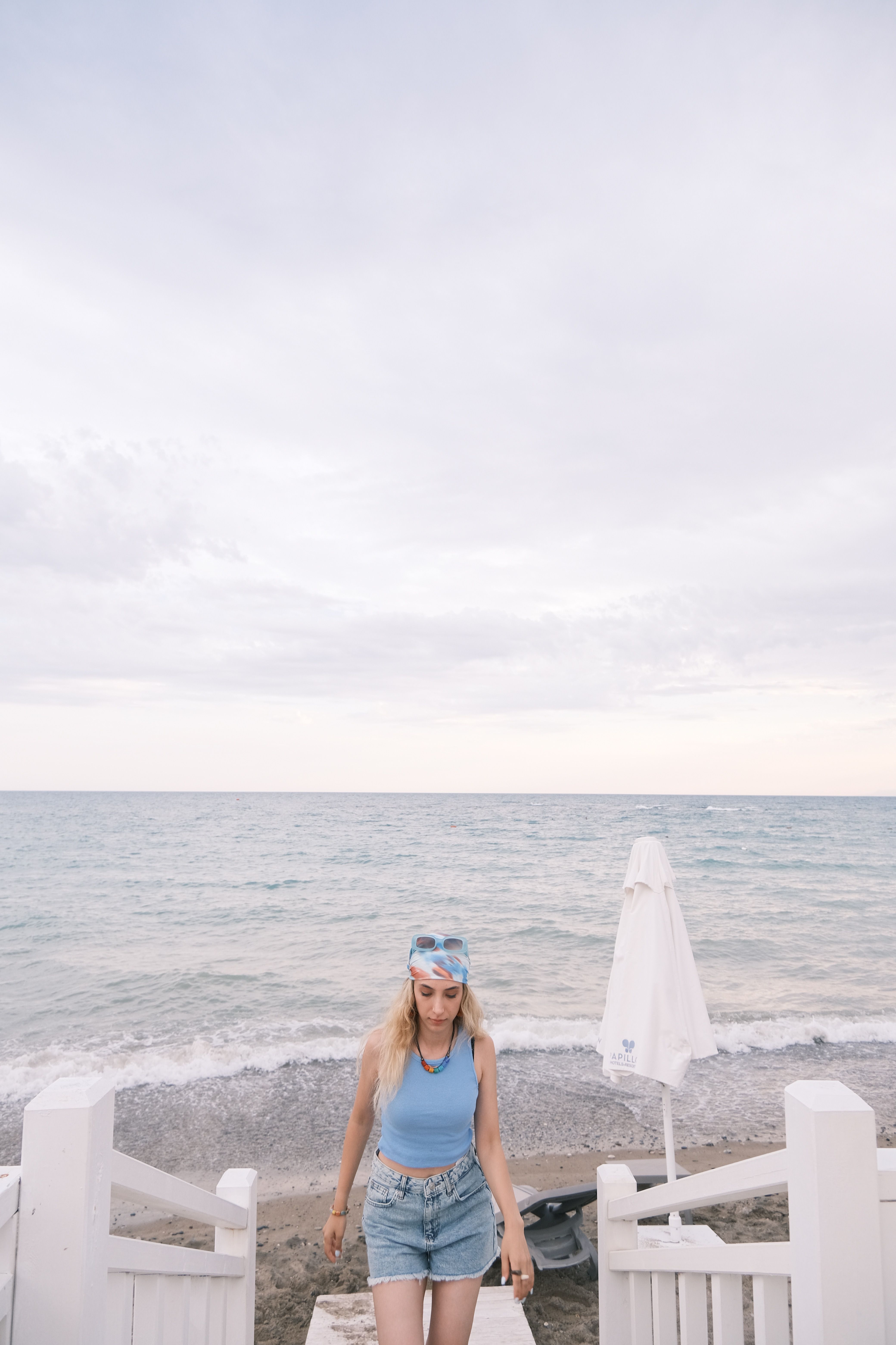 A young woman walks along a serene beach, enjoying a peaceful summer day by the ocean.