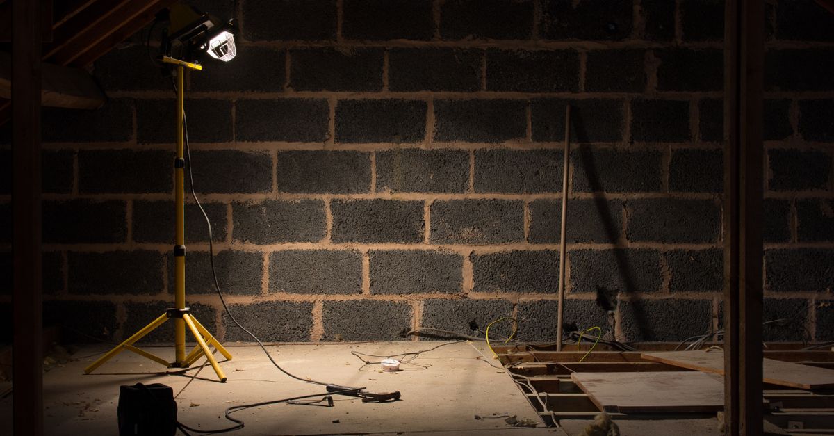 A dimly lit attic space under renovation with a construction lamp illuminating the scene.