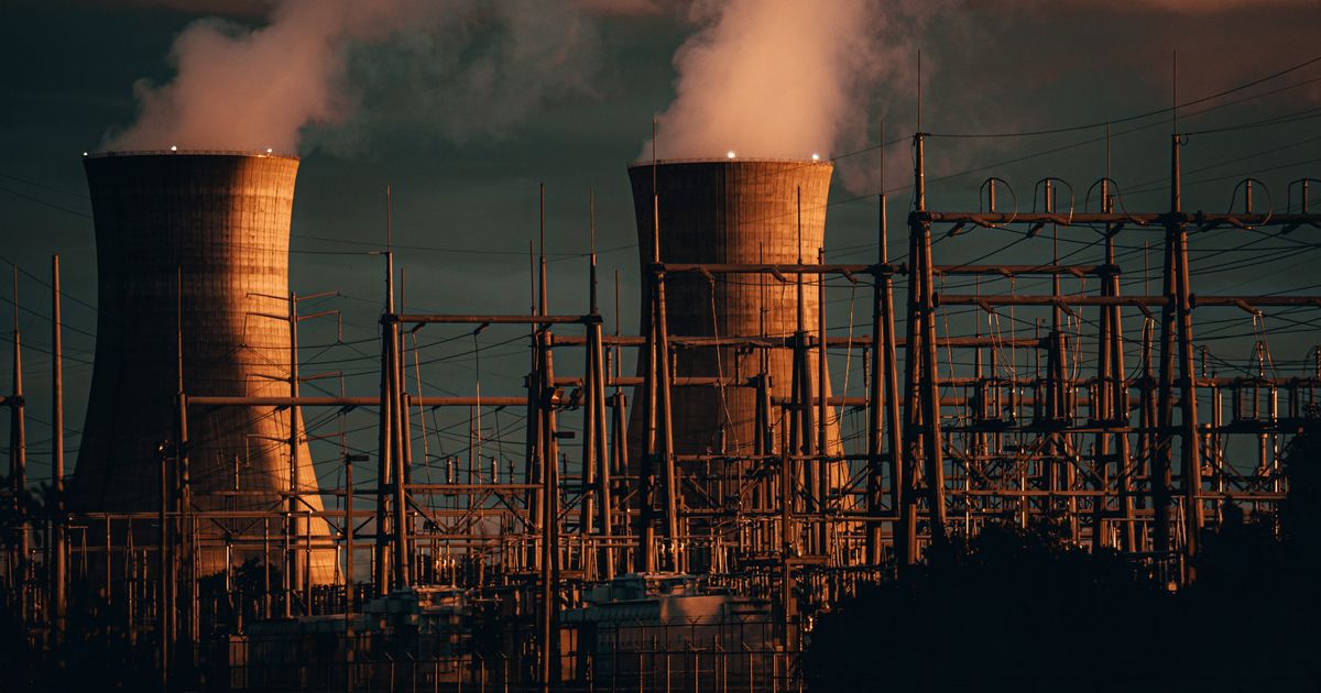 Cooling towers of a nuclear power plant emitting steam at sunset.