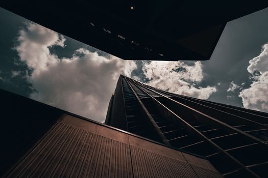 A striking low angle architectural shot of a modern skyscraper reaching into cloudy skies.