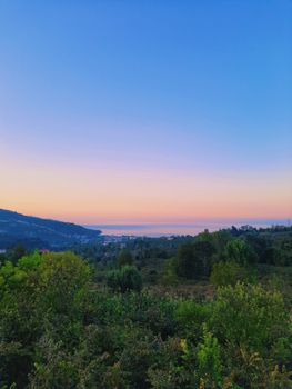 A serene landscape with hills, ocean view, and lush greenery at twilight, perfect for nature lovers.