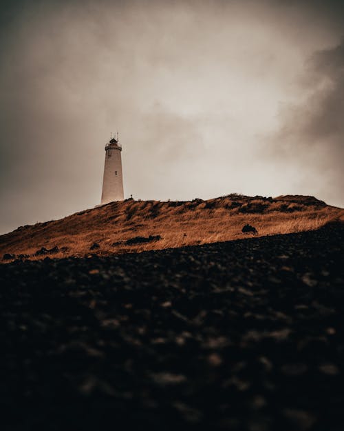 A Lighthouse on a Hill under a Cloudy Sky
