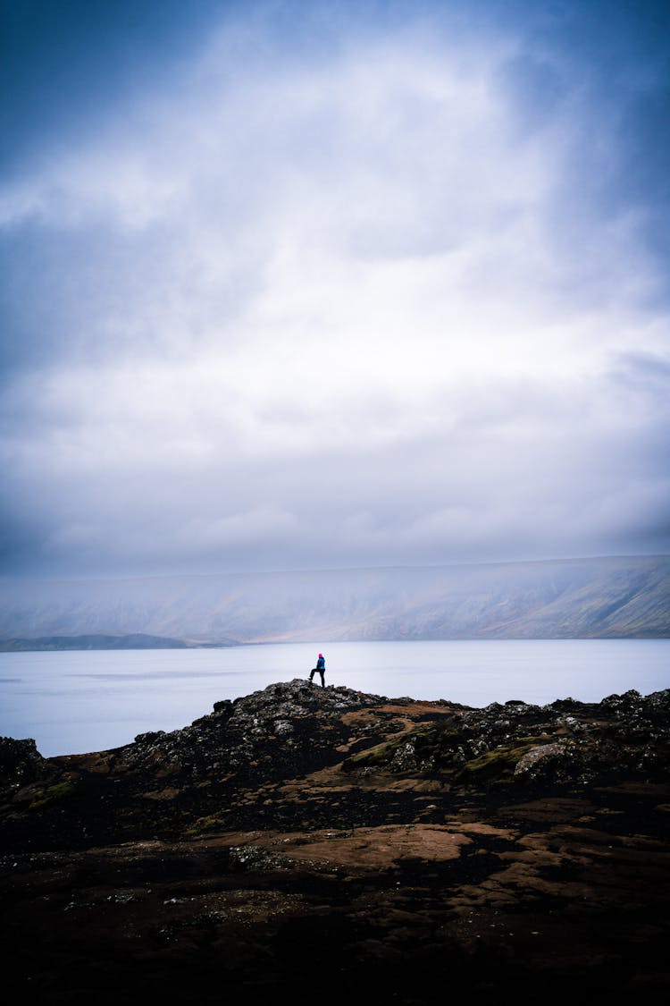 Person Standing On A Rock At A Sea Bay Shore