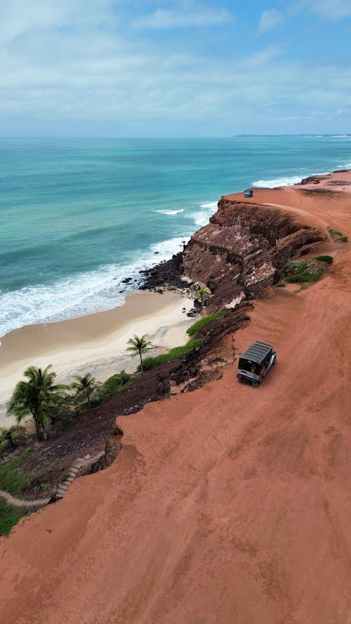 Car with Tourists on Dirt Road Along the Cliff